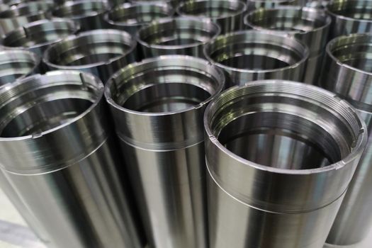 A close-up shot of shiny steel aerospace cnc turned tubes in a batch with selective focus and background blur.