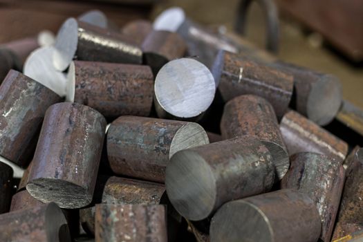 a pile of raw steel short bars cutted by saw- workpieces prepaired for forging, close-up with selective focus and background blur