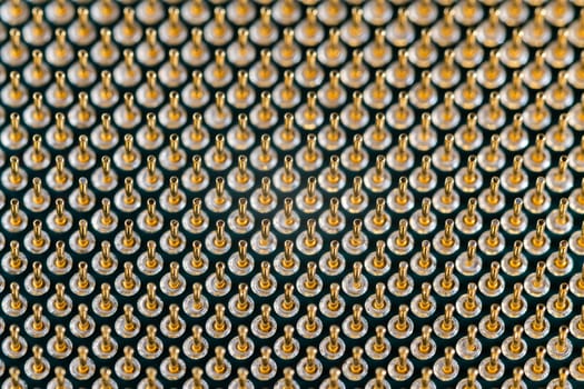 Close-up full frame view of gold plated microprocessor pin array. Abstract electronic technological background with selective focus.