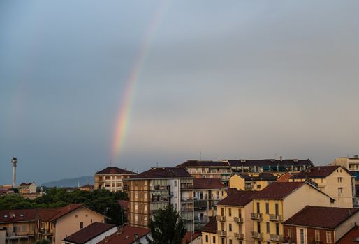 Turin, Piedmont, Italy. June 2020. After a summer storm in the northern suburbs, a rainbow emerges from the roof of a small house on the horizon and embraces the city.