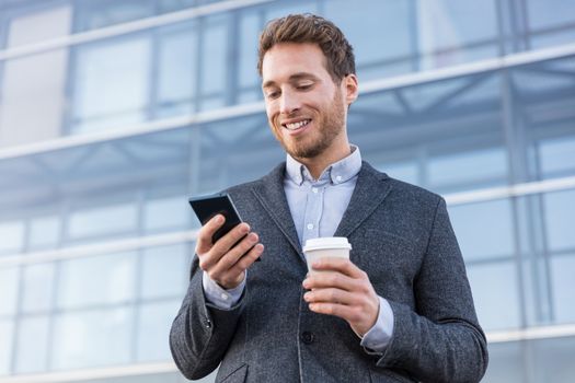 Business man looking at phone texting sms message text drinking coffee on morning break at work office. Businessman lifestyle.