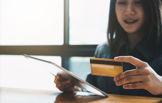 Young woman holding credit card and using tablet computer. Online shopping concept.