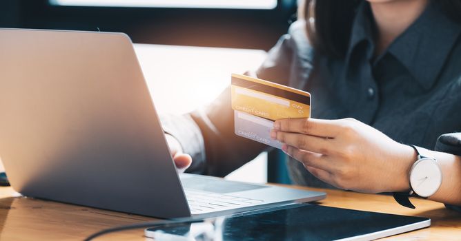 Young woman holding credit card and using laptop computer. Online shopping concept.