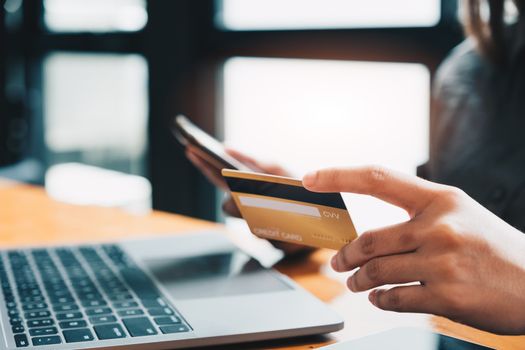 Young woman holding credit card and using laptop computer. Online shopping concept.