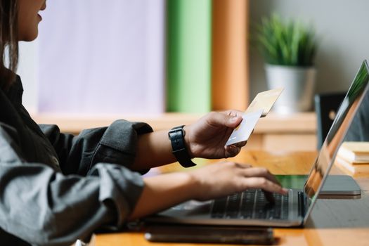 Young woman holding credit card and using laptop computer. Online shopping concept.