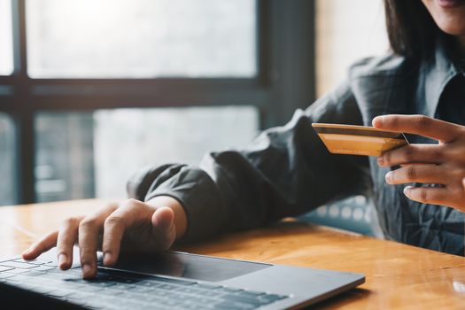 Young woman holding credit card and using laptop computer. Online shopping concept.