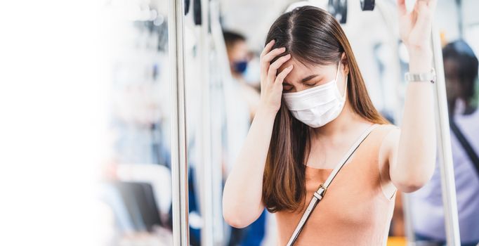 Young Asian woman passenger wearing surgical mask and Having a headache in subway train when traveling in big city at Covid19 outbreak, Infection and Pandemic,new normal and illness prevention concept