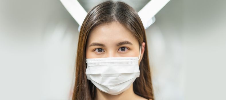 Young Asian woman passenger wearing surgical mask and looking at camera in subway train when traveling in big city at Covid19 outbreak, Infection and Pandemic, social distancing and new normal concept