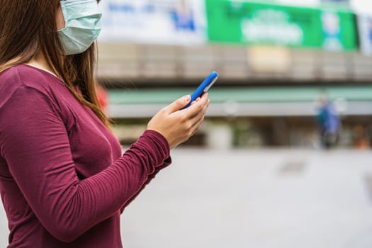 Closeup Asian woman hand using smart mobile phone with safety medical face mask for prevent Coronavirus or Covid19 Outbreak when travel to work in business downtown, Health care and infection concept