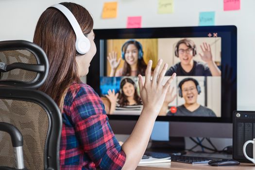 Rear View of Asian Business woman say hello with teamwork colleague in video conference when Coronavirus outbreak, Covid-19 pandemic, online meeting, Social distancing and new normal concept