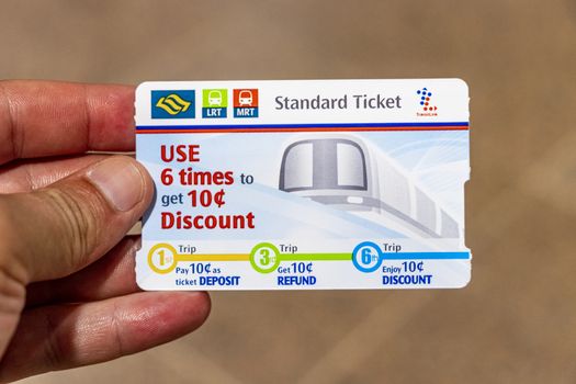 MRT and LRT Standard Ticket metro and subway in Singapore. Card hold in hand.