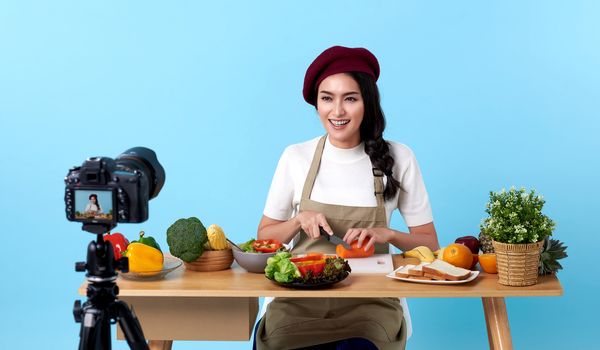 Happy asian young woman in fashion look style and shooting video with camera cooking food healthy is blogger presenting for social people.Her is influencer in social online.