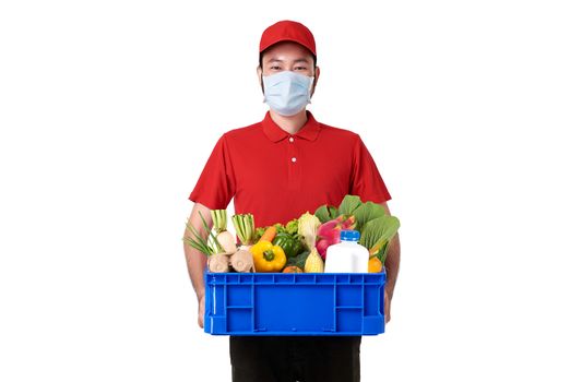 Asian delivery man wearing face mask in red uniform holding fresh food basket isolated over white background. express delivery service during covid19.