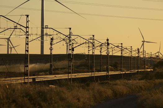 Train tracks superimposed on a landscape of silhouettes of operating wind turbines in the Ribera Alta del ebro, in Aragon, Spain.