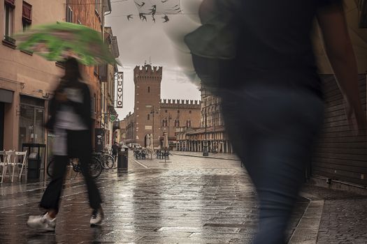 FERRARA, ITALY 29 JULY 2020 : Evocative view of the street that leads to Piazza Trento Trieste in Ferrara in Italy with people in their daily lives