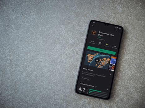 Lod, Israel - July 8, 2020: Adobe Illustrator Draw app play store page on the display of a black mobile smartphone on ceramic stone background. Top view flat lay with copy space.