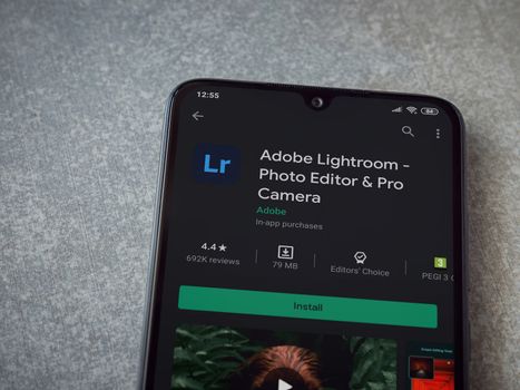 Lod, Israel - July 8, 2020: Adobe Lightroom - Photo Editor and Pro Camera app play store page on the display of a black mobile smartphone on ceramic stone background. Top view flat lay with copy space.