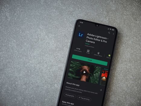 Lod, Israel - July 8, 2020: Adobe Lightroom - Photo Editor and Pro Camera app play store page on the display of a black mobile smartphone on ceramic stone background. Top view flat lay with copy space.