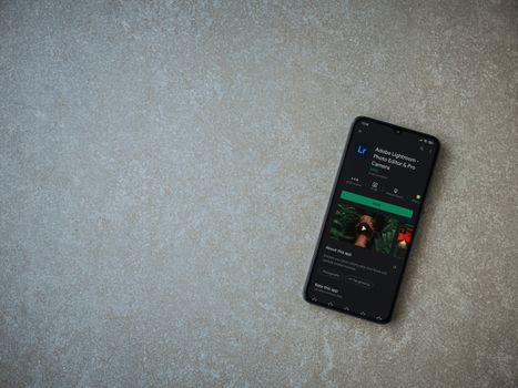 Lod, Israel - July 8, 2020: Adobe Lightroom - Photo Editor and Pro Camera app play store page on the display of a black mobile smartphone on ceramic stone background. Top view flat lay with copy space.