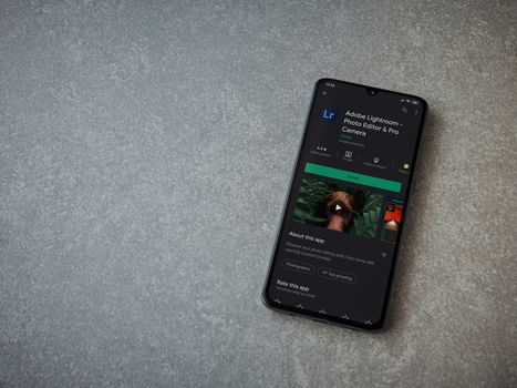 Lod, Israel - July 8, 2020: Adobe Lightroom - Photo Editor and Pro Camera app play store page on the display of a black mobile smartphone on ceramic stone background. Top view flat lay with copy space.