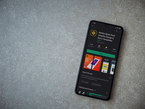 Lod, Israel - July 8, 2020: Adobe Spark Post - Graphic Design and Story Templates app play store page on the display of a black mobile smartphone on ceramic stone background.Top view flat lay with copy space