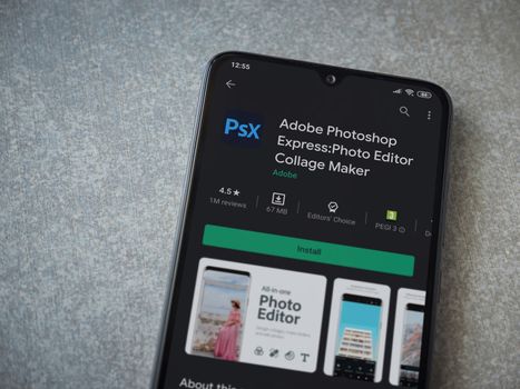 Lod, Israel - July 8, 2020: Adobe Photoshop Express Photo Editor app play store page on the display of a black mobile smartphone on ceramic stone background. Top view flat lay with copy space.