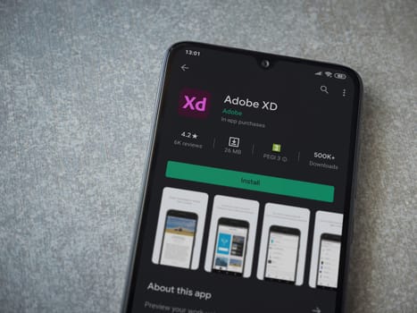Lod, Israel - July 8, 2020: Adobe XD app play store page on the display of a black mobile smartphone on ceramic stone background. Top view flat lay with copy space. 