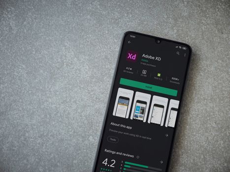 Lod, Israel - July 8, 2020: Adobe XD app play store page on the display of a black mobile smartphone on ceramic stone background. Top view flat lay with copy space. 
