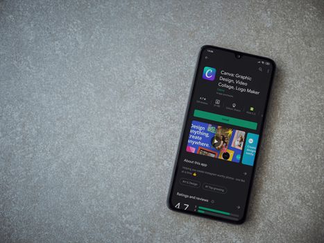Lod, Israel - July 8, 2020: Canva - Graphic Design app play store page on the display of a black mobile smartphone on ceramic stone background. Top view flat lay with copy space. 