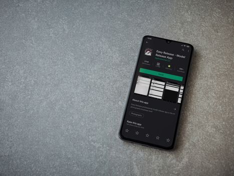 Lod, Israel - July 8, 2020: Easy Release Pro - Model Release app play store page on the display of a black mobile smartphone on ceramic stone background. Top view flat lay with copy space. 