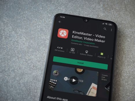 Lod, Israel - July 8, 2020: KineMaster - Video Editor and Movie Maker app play store page on the display of a black mobile smartphone on ceramic stone background. Top view flat lay with copy space.