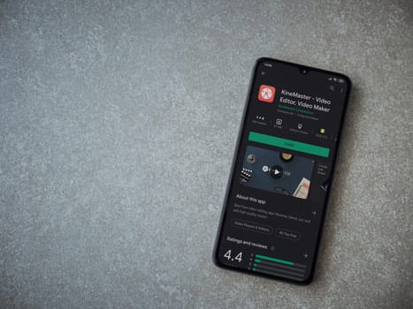 Lod, Israel - July 8, 2020: KineMaster - Video Editor and Movie Maker app play store page on the display of a black mobile smartphone on ceramic stone background. Top view flat lay with copy space.