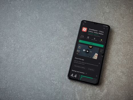 Lod, Israel - July 8, 2020: KineMaster - Video Editor and Movie Maker app play store page on the display of a black mobile smartphone on ceramic stone background. Top view flat lay with copy space.