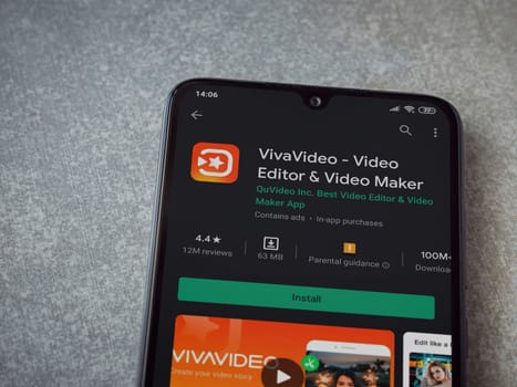 Lod, Israel - July 8, 2020: VivaVideo - Video Editor and Movie Maker app play store page on the display of a black mobile smartphone on ceramic stone background. Top view flat lay with copy space.