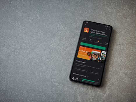 Lod, Israel - July 8, 2020: VivaVideo - Video Editor and Movie Maker app play store page on the display of a black mobile smartphone on ceramic stone background. Top view flat lay with copy space.