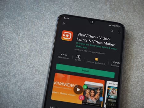 Lod, Israel - July 8, 2020: VivaVideo - Video Editor and Movie Maker app play store page on the display of a black mobile smartphone on ceramic stone background. Top view flat lay with copy space.