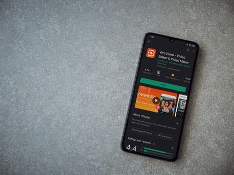 Lod, Israel - July 8, 2020: VivaVideo - Video Editor and Movie Maker app play store page on the display of a black mobile smartphone on ceramic stone background. Top view flat lay with copy space.