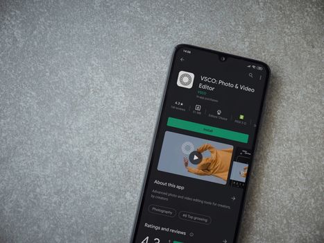 Lod, Israel - July 8, 2020: VSCO - Photo and Video Editor app play store page on the display of a black mobile smartphone on ceramic stone background. Top view flat lay with copy space. 