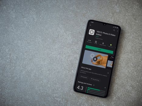 Lod, Israel - July 8, 2020: VSCO - Photo and Video Editor app play store page on the display of a black mobile smartphone on ceramic stone background. Top view flat lay with copy space. 