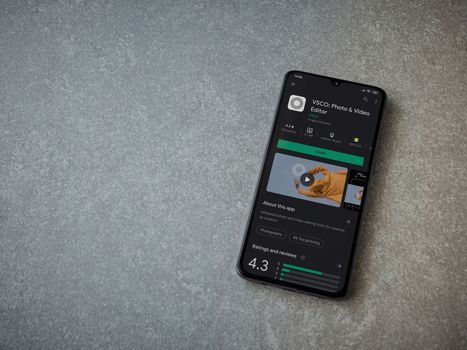 Lod, Israel - July 8, 2020: VSCO - Photo and Video Editor app play store page on the display of a black mobile smartphone on ceramic stone background. Top view flat lay with copy space. 