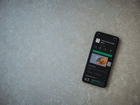 Lod, Israel - July 8, 2020: VSCO - Photo and Video Editor app play store page on the display of a black mobile smartphone on ceramic stone background. Top view flat lay with copy space. 