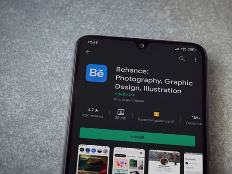 Lod, Israel - July 8, 2020: Adobe Behance app play store page on the display of a black mobile smartphone on ceramic stone background. Top view flat lay with copy space. 