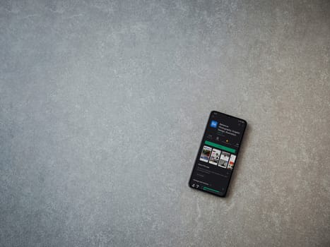 Lod, Israel - July 8, 2020: Adobe Behance app play store page on the display of a black mobile smartphone on ceramic stone background. Top view flat lay with copy space. 