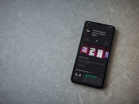 Lod, Israel - July 8, 2020: Adobe Capture - Vector and Pattern Maker app play store page on the display of a black mobile smartphone on ceramic stone background. Top view flat lay with copy space.
