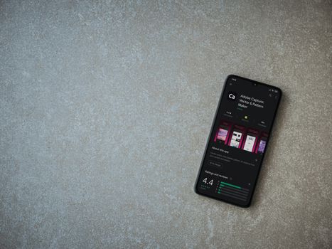 Lod, Israel - July 8, 2020: Adobe Capture - Vector and Pattern Maker app play store page on the display of a black mobile smartphone on ceramic stone background. Top view flat lay with copy space.
