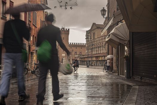 FERRARA, ITALY 29 JULY 2020 : Evocative view of the street that leads to Piazza Trento Trieste in Ferrara in Italy with people in their daily lives