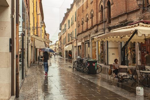 FERRARA, ITALY 29 JULY 2020 : Alley with people walking in Ferrara in Italy