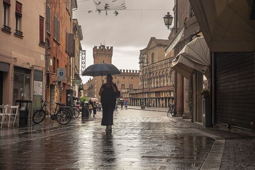 FERRARA, ITALY 29 JULY 2020 : Evocative view of the street that leads to Piazza Trento Trieste in Ferrara in Italy with people in their daily lives