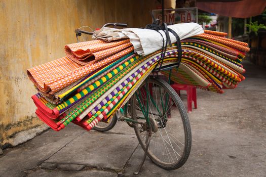 Hoi An Vietnam 24/12/2013 overloaded bicycle with floor coverings, mats and fabrics transporting goods. 2 wheel vehicles with huge amounts of products transporting around the city. High quality photo