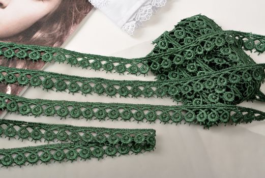 Tapes of green gentle guipure, beauty lace fabric on light background. Elastic material. Using for Atelier and needlework store.